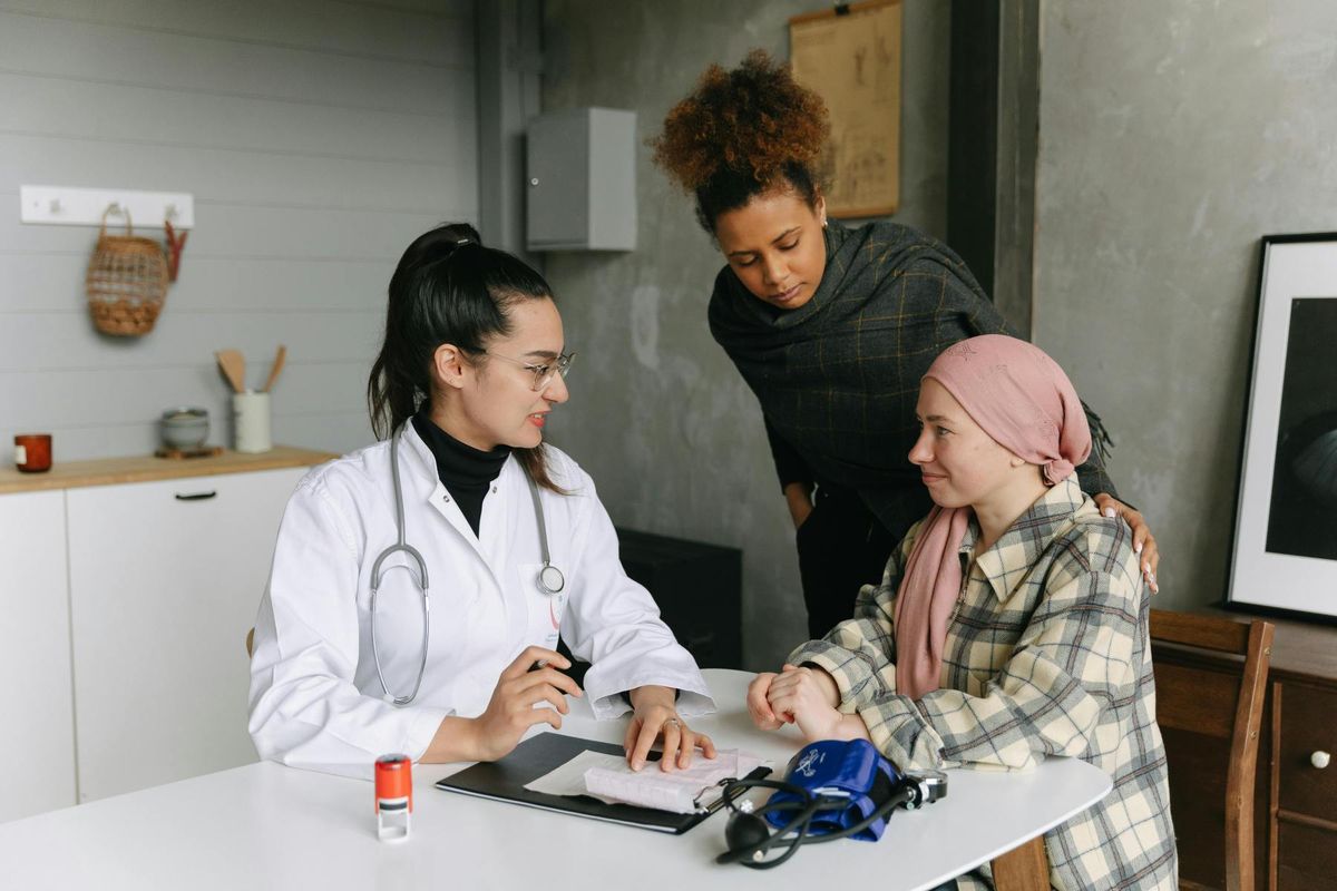 A care team supports a smiling patient at a kitchen table