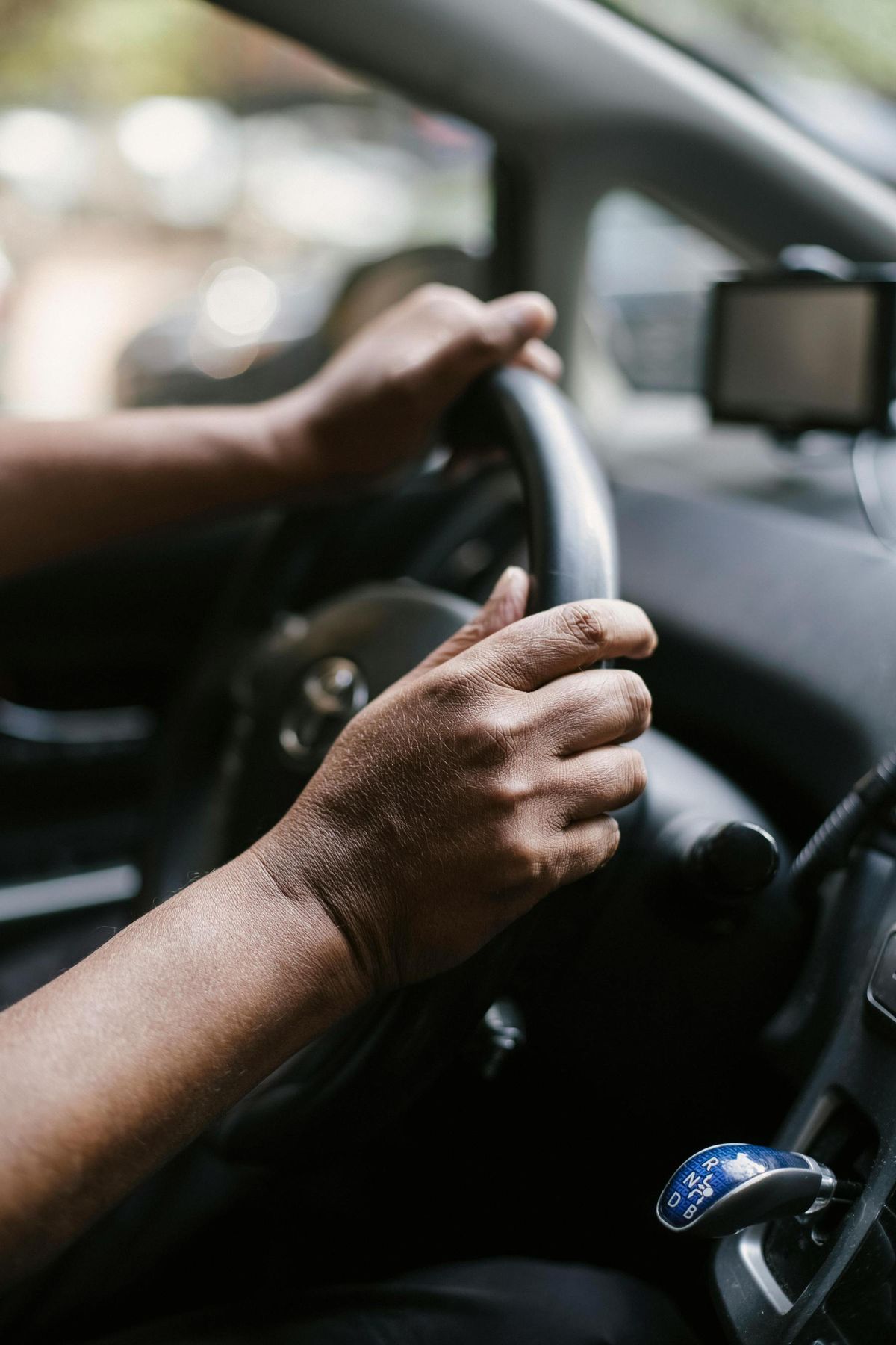 Hands on a steering wheel during a daytime drive