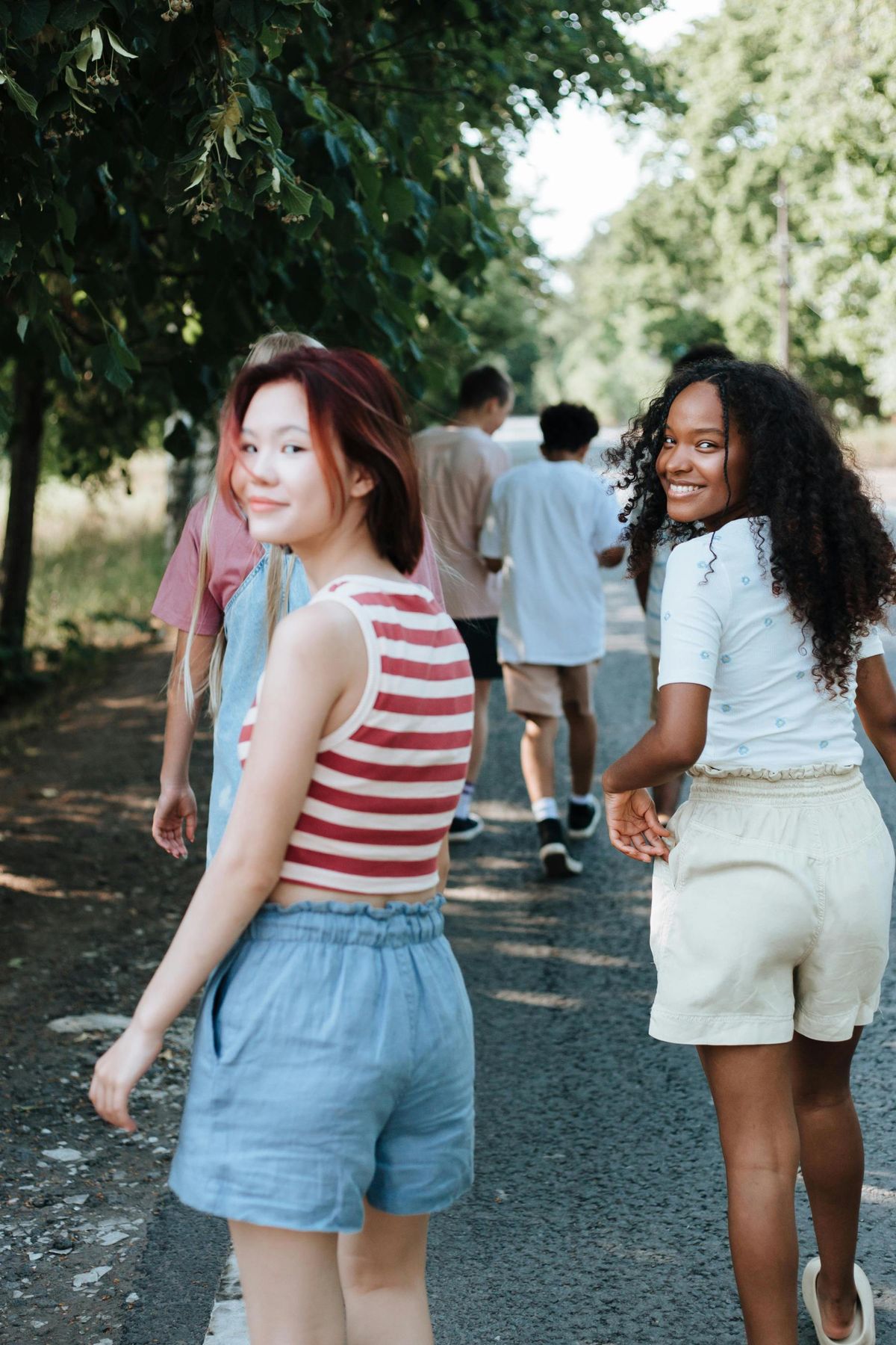Three friends walk together down a tree-lined street